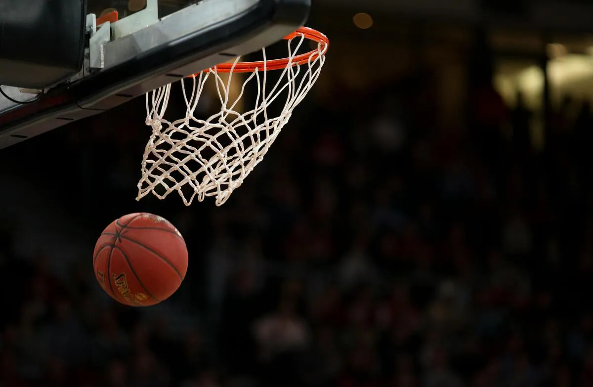 A basketball dropping through the net in a packed arena