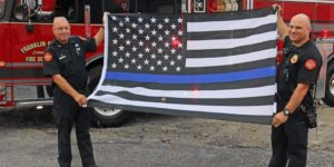 Two fire fighters holding the American flag