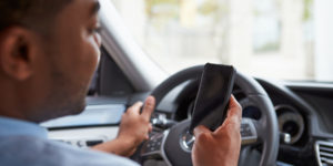 Person driving and looking at their phone at the same time in danger of a car accident