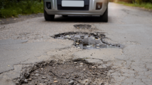 car on pothole filled road